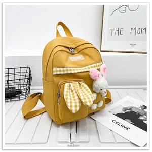 Detail view of bright yellow kids backpack with rabbit ears and plush bunny charm