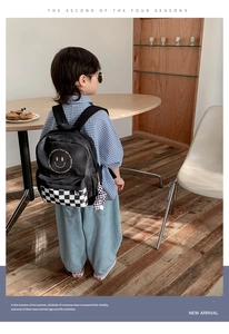 Detail of kids black nylon backpack with yellow smiley face and checkerboard pattern