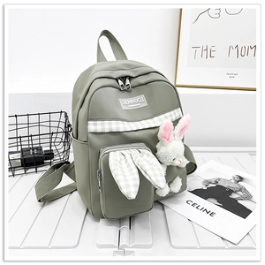 Detail view of green canvas backpack featuring cute bunny ears and a plush rabbit charm