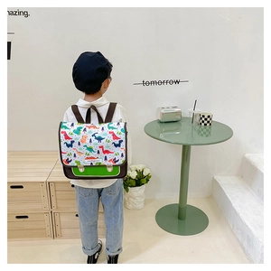 Detailansicht Kinderrucksack in Weiß mit bunten Dino-Prints und grünem Leder-Bodenakzent
