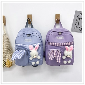 Detail of cute canvas backpacks with plush bunny dolls and checkered stripes for kids