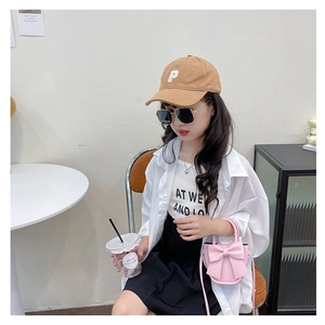 Girl wearing a pink crossbody bag with a large decorative bow in a cafe setting