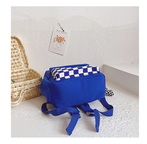 Detail of navy blue kids backpack featuring black and white checkerboard front pocket
