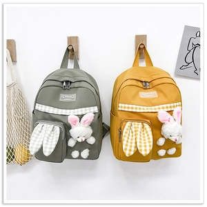 Detail showing grey and yellow canvas backpacks with plush bunny ears and decorative straps