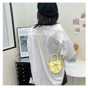 Detail showing the mini yellow PU leather crossbody bag with a large decorative bow