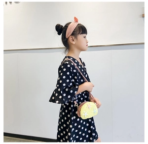 Detailed view of kids polka dot dress styled with a yellow star crossbody bag