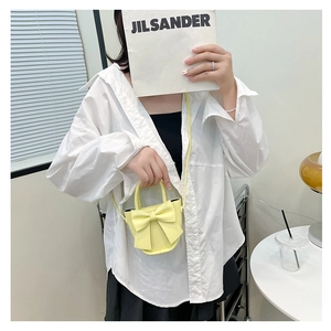 Detail showing a yellow mini PU leather crossbody bag with a large bow held by a model