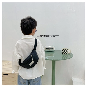 Detailansicht der schwarzen Kinder-Brusttasche mit Textur und weißem Fashion-Label