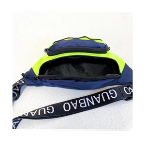 Détail du sac de poitrine bleu marine et vert néon avec sangle lettrée et zip ouvert