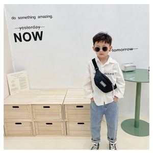 Detail der schwarzen Kinder-Schachbrett-Brusttasche mit FASHION-Patch an einem Jungen