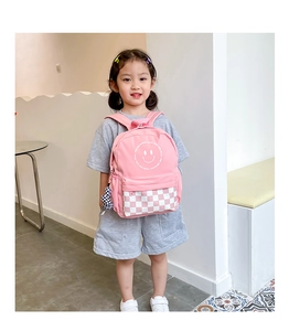 Close-up of pink kids backpack featuring checkerboard pattern and smiley face logo detail