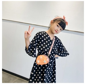 Detail of child wearing an orange sequin shell-shaped crossbody bag with a starfish accent