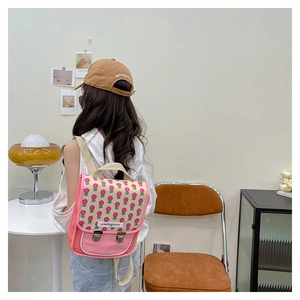 Nahaufnahme des rosa geblümten Kinderrucksacks mit Metallschnalle und gewebten Gurten
