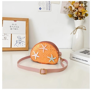 Close-up of orange sequin mini crossbody bag with star decor on a white table