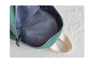 Close-up of green canvas kids backpack with gray lining and ivory woven strap details