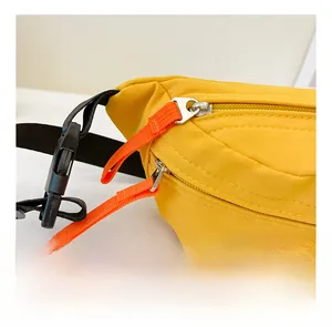 Detail der gelben Nylon-Brusttasche mit Sport-Logo, orangefarbenen Zippern und Schnalle