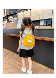 Detail of a bright yellow toddler backpack with cute cartoon bear and white wings design