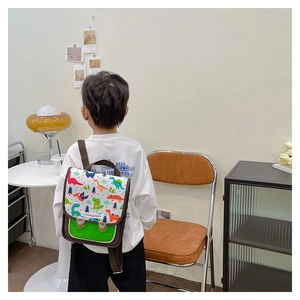 Detail eines Kinderrucksacks mit Dinosaurier-Print, grünem Lederboden und Metallschnallen