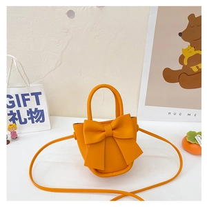 Detail of a vibrant orange PU leather bucket bag with a bow and long crossbody strap