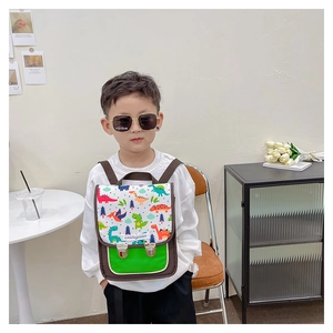 Detailansicht von Cartoon-Dino-Print und Metallschnallen am braunen Kinderrucksack