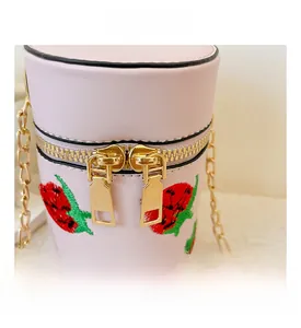 Details der rosa Zylindertasche mit Erdbeerstickerei und goldenen Doppelreißverschlüssen