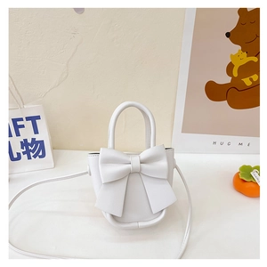 Detail of white PU bucket bag with large bow and crossbody strap on gift background