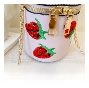 Detail der rosa Zylindertasche mit Erdbeerstickerei und goldenem Doppel-Reißverschluss
