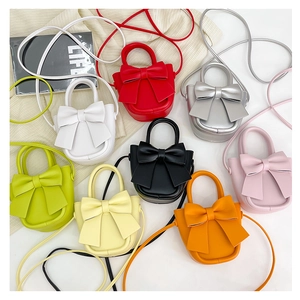 Flat lay of mini PU leather bow crossbody bags in eight vibrant assorted colors