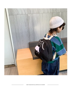 Close-up of black canvas backpack for kids featuring cute bear print and white wings