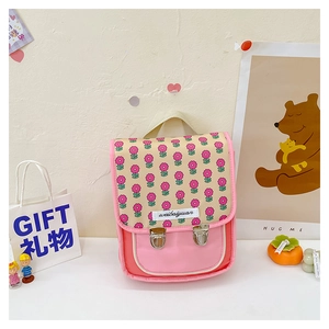 Detail eines rosa Kinderrucksacks mit Blumenmuster, Metallschnallen und Geschenkdeko