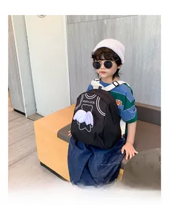 Detail of cute black canvas kids backpack with white 3D wings and bear print decoration
