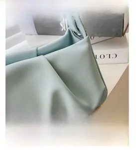 Macro shot of mint green pleated leather handbag showing precise stitching and matte texture