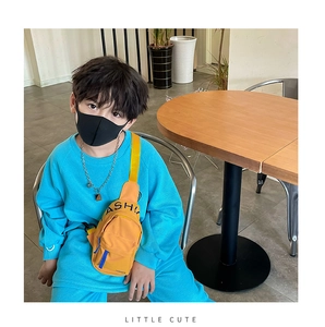 Detail of kids yellow canvas chest bag featuring fashion text and adjustable blue strap
