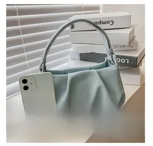 Detail view of a light blue pleated cloud bag with rounded handle and ruched faux leather