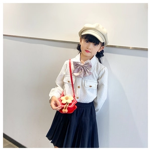 Detail of red flower crossbody bag paired with a plaid shirt and navy pleated skirt