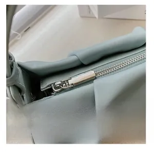 Close-up of the smooth metal zipper and fine stitching on this blue pleated cloud bag
