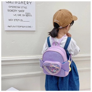 Detail of purple sequin backpack with wings and heart pocket worn by a child