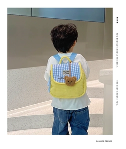 Vue arrière d'un enfant portant un sac à dos matelassé jaune avec rabat à carreaux bleus