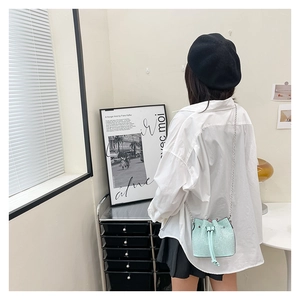 Mint green rhinestone bucket bag with silver chain worn over white shirt and black beret