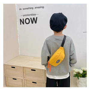 Details einer gelben Jungen-Brusttasche mit verstellbarem Gurt und orangefarbenen Zippern