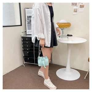 Detail of mint green woven bucket bag with silver chain strap and drawstring closure