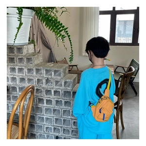 Detail of a bright yellow kids' canvas chest bag with black FASHION lettering and blue straps