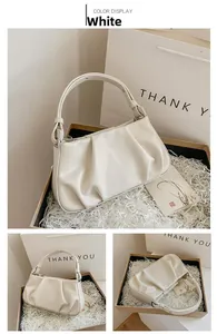 Close-up of cream pleated shoulder bag inside an elegant gift box with filler