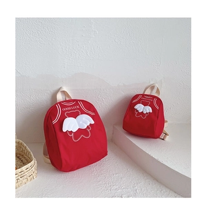 Detail view of two red canvas backpacks with angel wings and Good Luck print