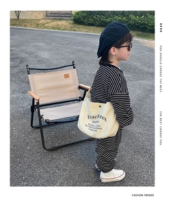 Young boy wearing a stylish cream canvas crossbody bag with trendy stripe outfit
