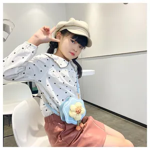 Close-up of sky blue flower-shaped PU leather crossbody bag with soft pink pompons