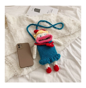 Macro detail of a handmade blue crochet doll bag with bright red lips and bow accents