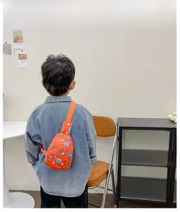 Detail of adjustable orange strap and dinosaur print on lightweight canvas kids' chest bag