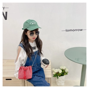 Kid modeling a red rhinestone bucket bag with silver chain strap in a lifestyle setting