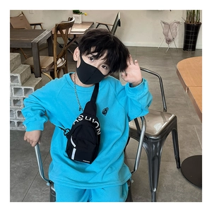 Close-up of kids' blue waffle knit sweatshirt with a black fashion chain chest bag